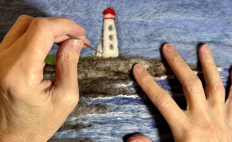 hands needle felting a landscape art work